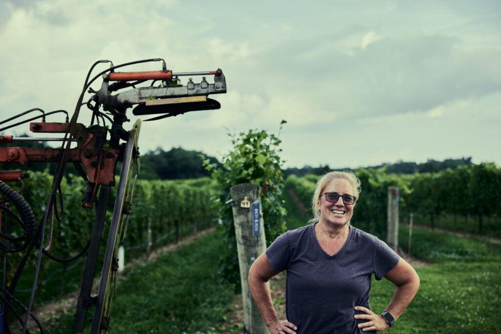 Farmer Jennie Schmidt stands in front of wine grapes in her Maryland vineyard